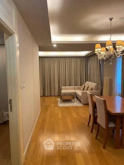 Spacious living room with elegant chandelier and wooden flooring in modern apartment.