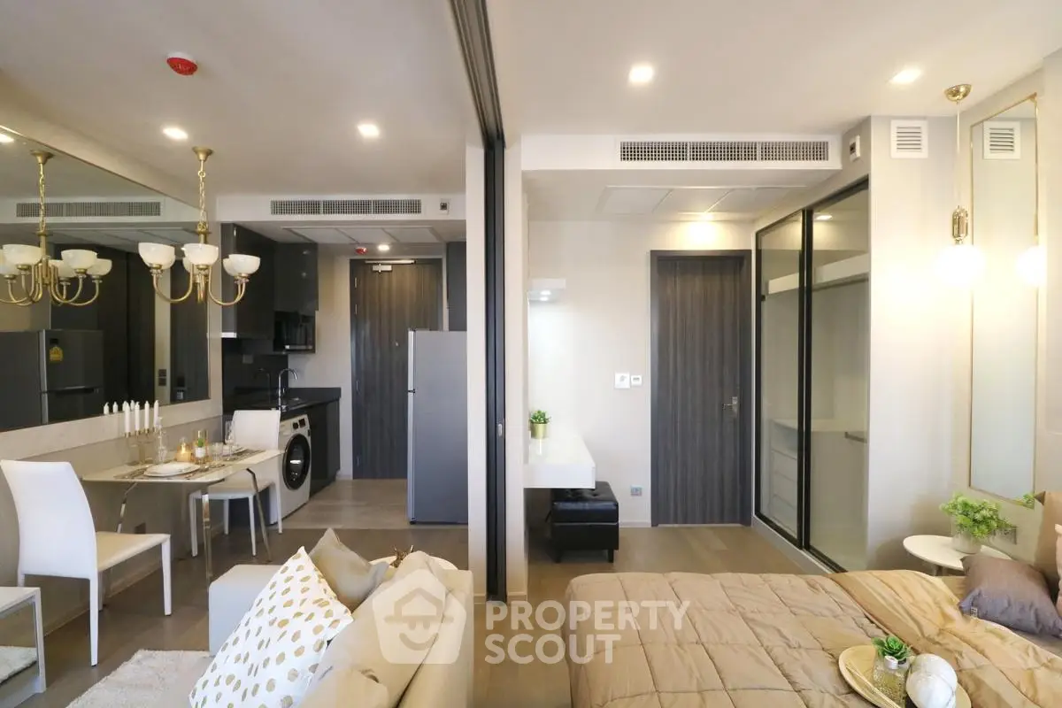 Modern open-plan living room and bedroom with elegant decor and dining area in a stylish apartment.