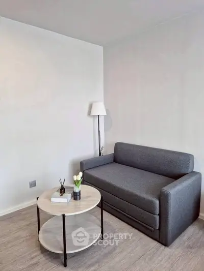 Modern minimalist living room with sleek gray sofa and round coffee table, perfect for cozy relaxation.
