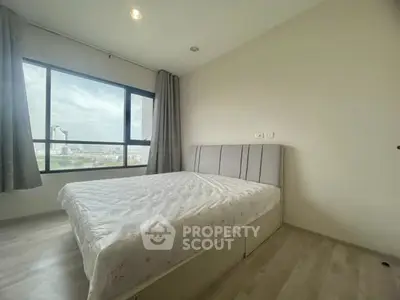 Bright bedroom with large window offering city views, featuring a comfortable bed and modern decor.