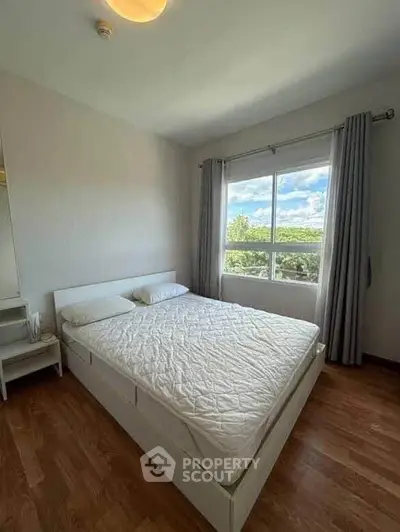 Bright bedroom with large window and scenic view, featuring a comfortable bed and wooden flooring.