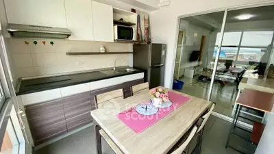Modern kitchen with dining area and open layout to living room, featuring sleek cabinets and appliances.