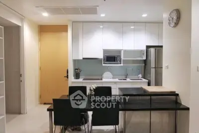 Modern kitchen with sleek white cabinets and dining area in contemporary apartment.