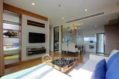 Spacious modern living room with open kitchen and dining area, featuring sleek furniture and natural light.