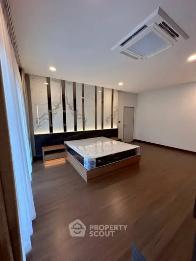 Spacious modern bedroom with elegant wood flooring and stylish wall design