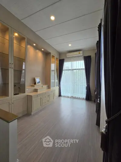 Spacious living room with elegant built-in cabinets and large window for natural light.