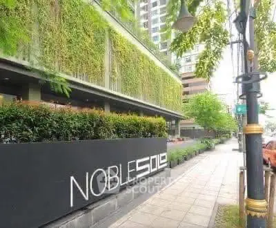 Modern building exterior with lush greenery and sleek signage