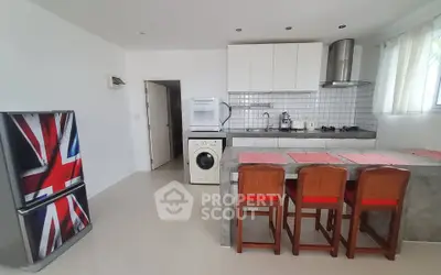 Modern kitchen with Union Jack fridge, washing machine, and breakfast bar seating.