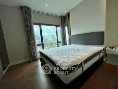 Spacious bedroom with large windows offering stunning city views and modern furnishings.