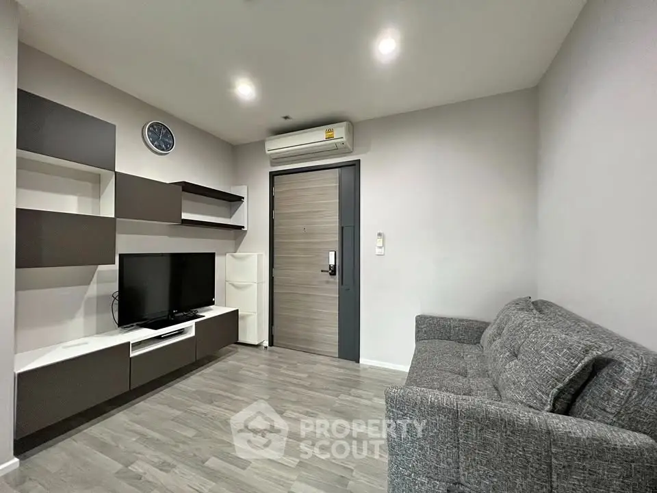 Modern living room with sleek furniture and wall-mounted TV in a cozy apartment.