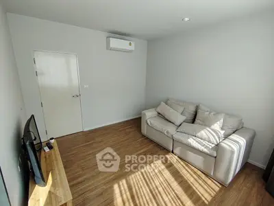 Cozy living room with modern sofa and wooden flooring, perfect for relaxation.