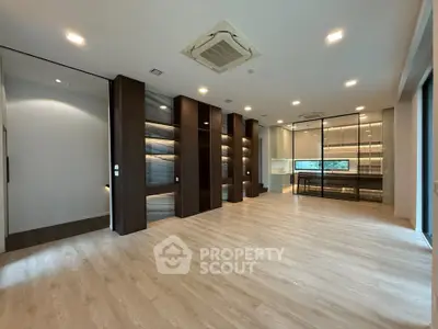 Spacious modern living room with elegant wooden flooring and built-in shelving, perfect for luxury living.