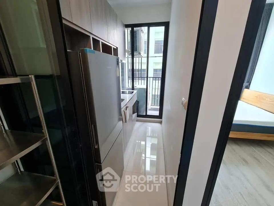 Modern compact kitchen with sleek appliances and large windows in a stylish apartment.