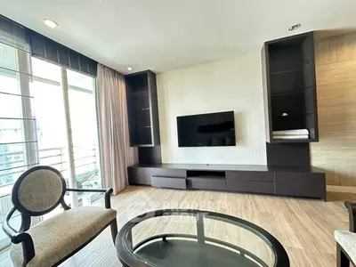Modern living room with sleek TV unit and large windows offering natural light.