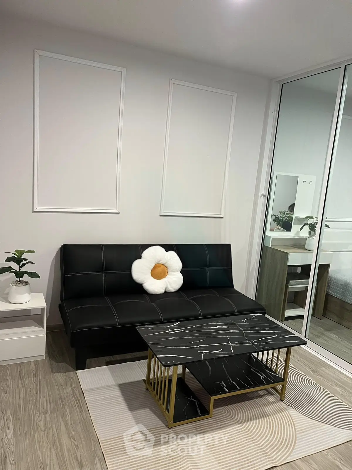 Modern living room with sleek black sofa, marble coffee table, and stylish decor in a contemporary apartment.