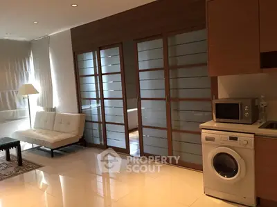 Modern living room with sliding glass doors, washing machine, and microwave in stylish apartment.