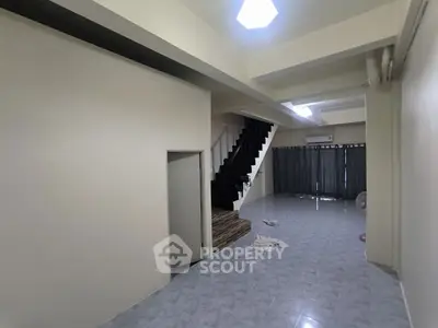 Spacious interior with modern staircase and tiled flooring, perfect for stylish living.