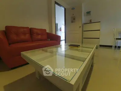 Modern living room with red sofa and glass coffee table in a cozy apartment.