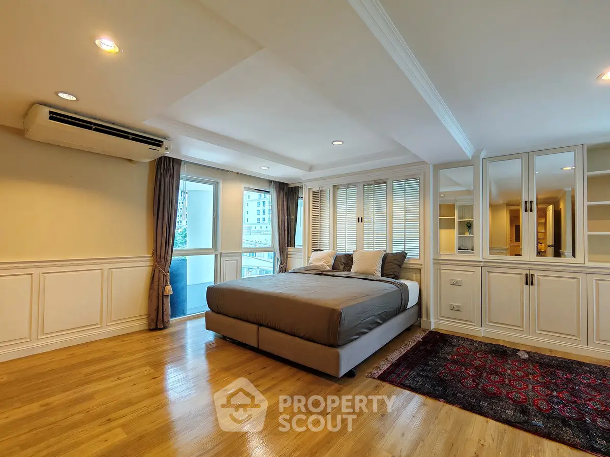 Spacious bedroom with elegant decor and large windows in modern apartment