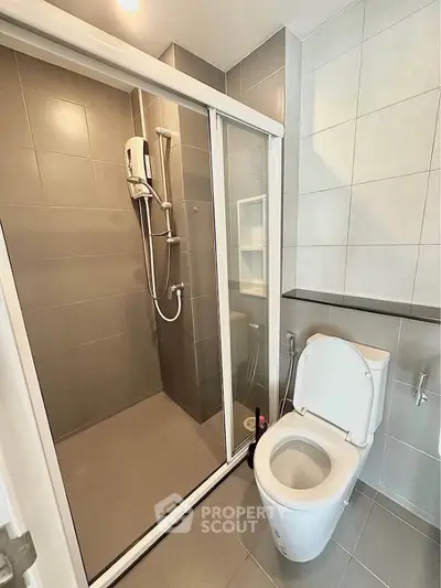 Modern bathroom with sleek shower and toilet in contemporary apartment.