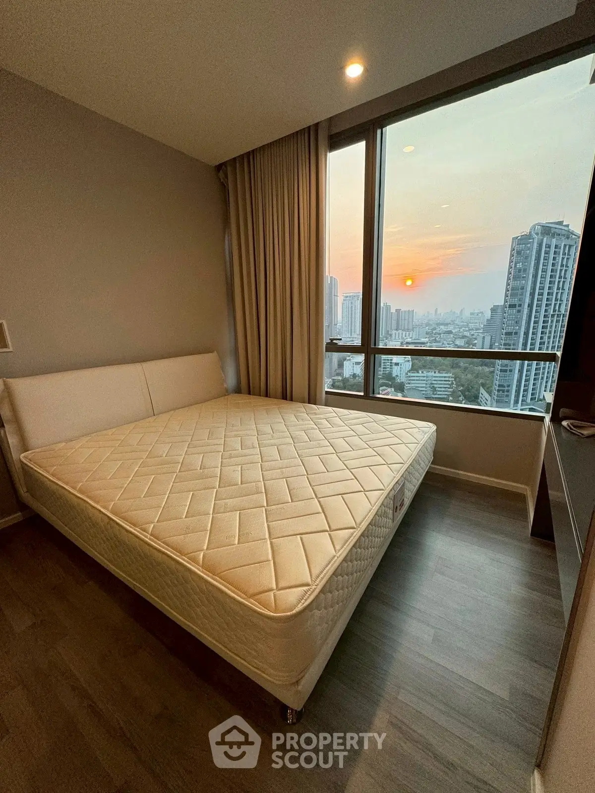 Modern bedroom with city view and large window, featuring a comfortable bed and elegant decor.