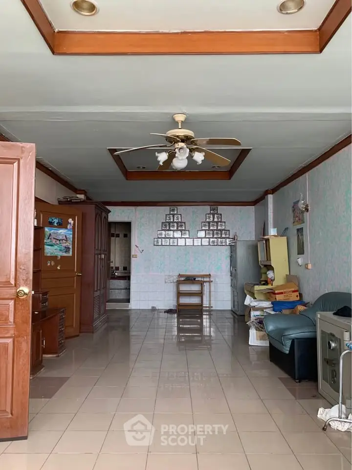 Spacious living room with ceiling fan and tiled floor, featuring cozy seating and wooden furniture.