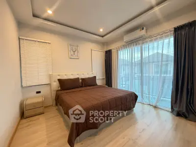 Spacious bedroom with modern decor and large windows offering natural light.