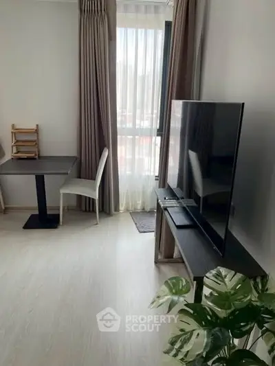 Modern living room with sleek TV setup and dining area, featuring large window and stylish decor.