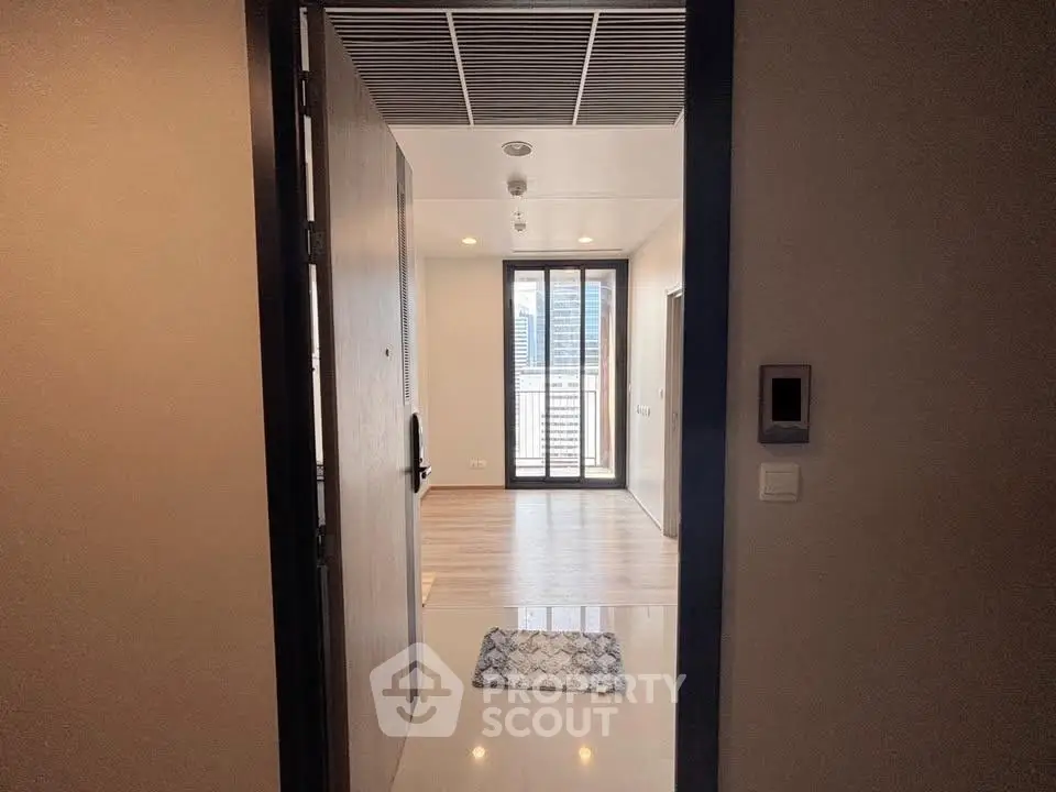 Modern apartment entrance with wooden flooring and large window view.