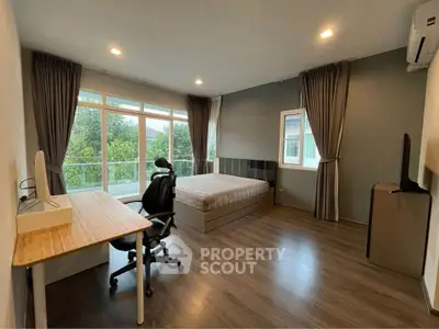 Spacious bedroom with modern furnishings and large windows overlooking greenery.