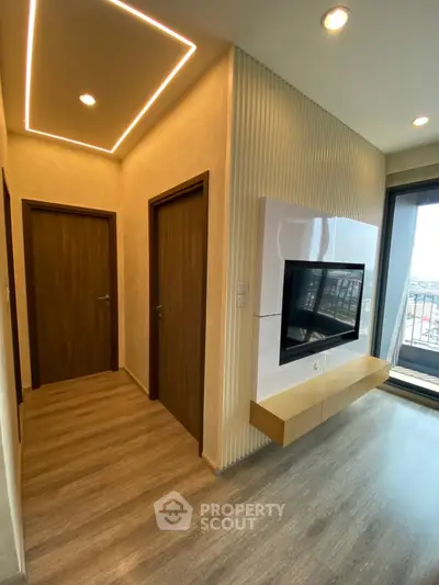 Modern living room with sleek TV setup and wooden flooring, featuring ambient ceiling lighting.