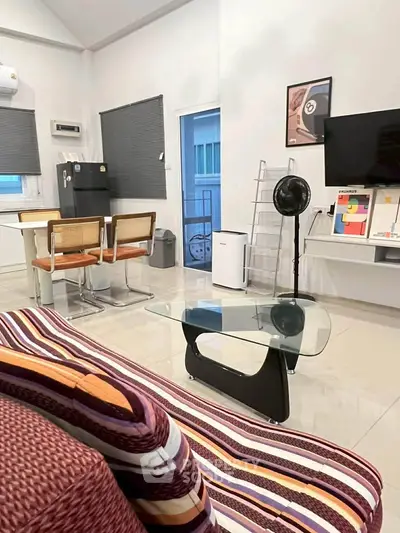 Modern living room with stylish furniture and contemporary decor, featuring a glass coffee table and wall-mounted TV.
