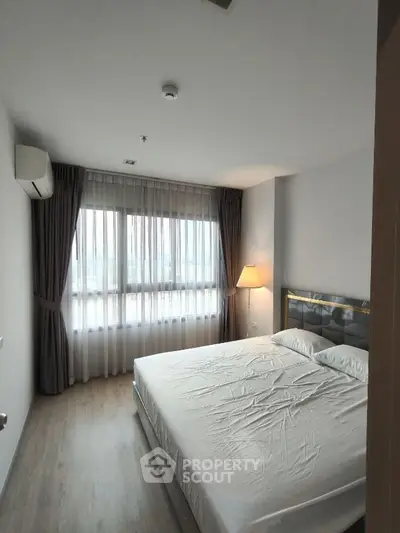 Spacious bedroom with large window and modern decor in a stylish apartment.