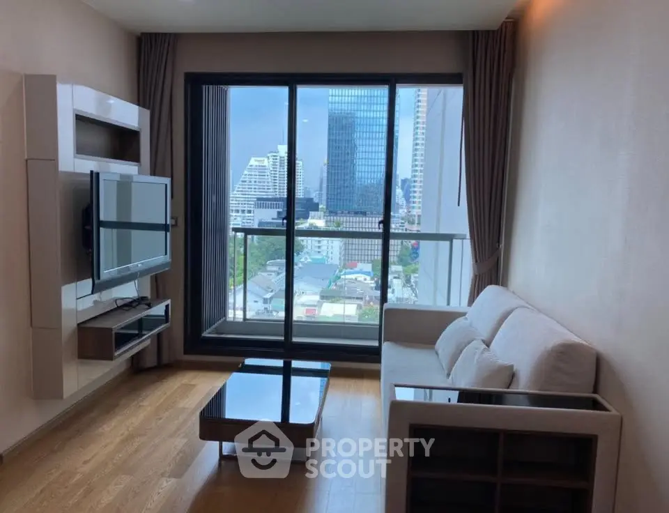 Modern living room with city view, featuring sleek furniture and large windows for natural light.