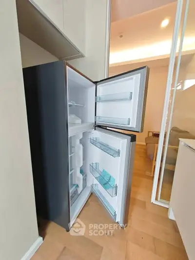 Modern kitchen with open fridge showcasing sleek design and ample storage space.