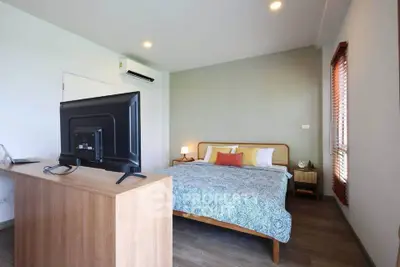 Spacious bedroom with modern decor and natural light, featuring a cozy bed and stylish furnishings.