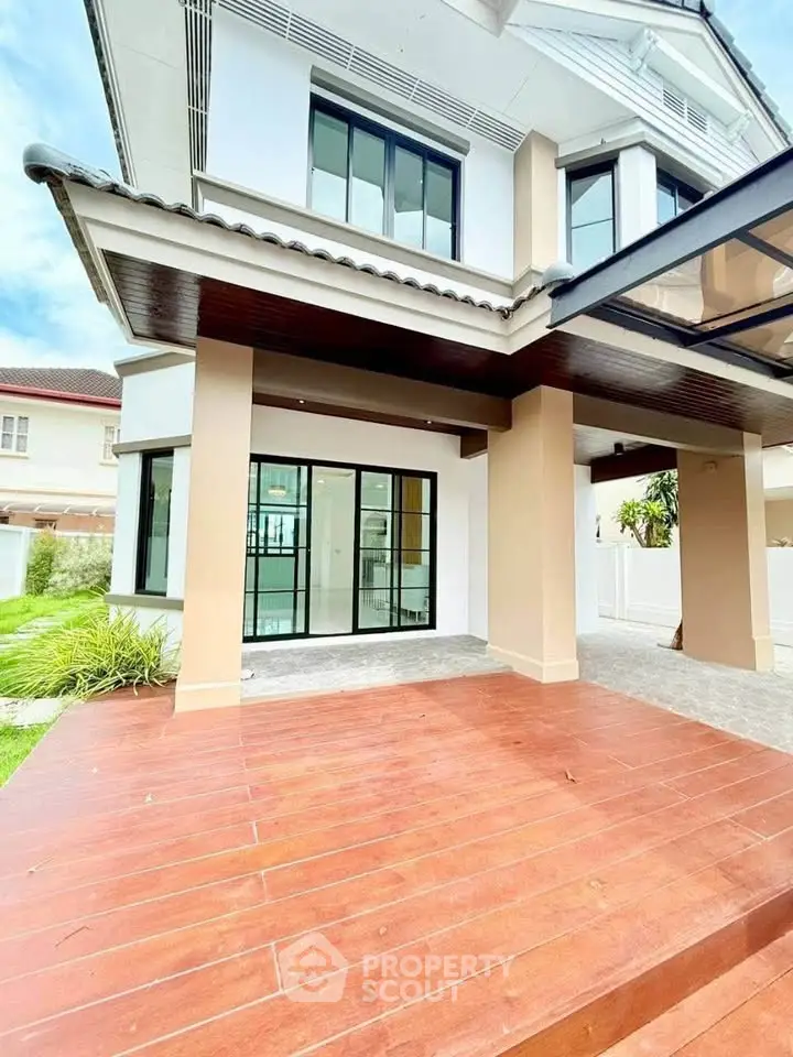 Stunning modern house exterior with spacious wooden deck and large glass doors, perfect for family living.
