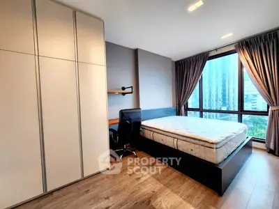 Modern bedroom with large window and city view, featuring sleek furniture and ample natural light.