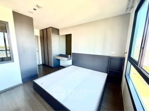 Modern bedroom with large windows and sleek design in high-rise apartment.