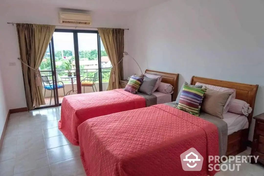 Spacious twin bedroom with large windows leading to a sunny balcony, featuring comfortable beds and a cozy seating area.