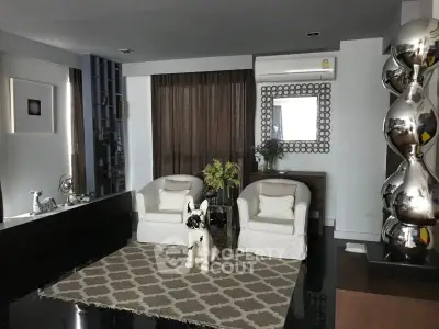 Stylish living room with modern decor and unique sculptures, featuring elegant seating and a chic rug.