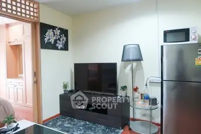 Modern living room with TV, stylish lamp, and stainless steel fridge