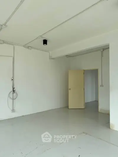 Spacious empty room with white walls and open door, ideal for customization.