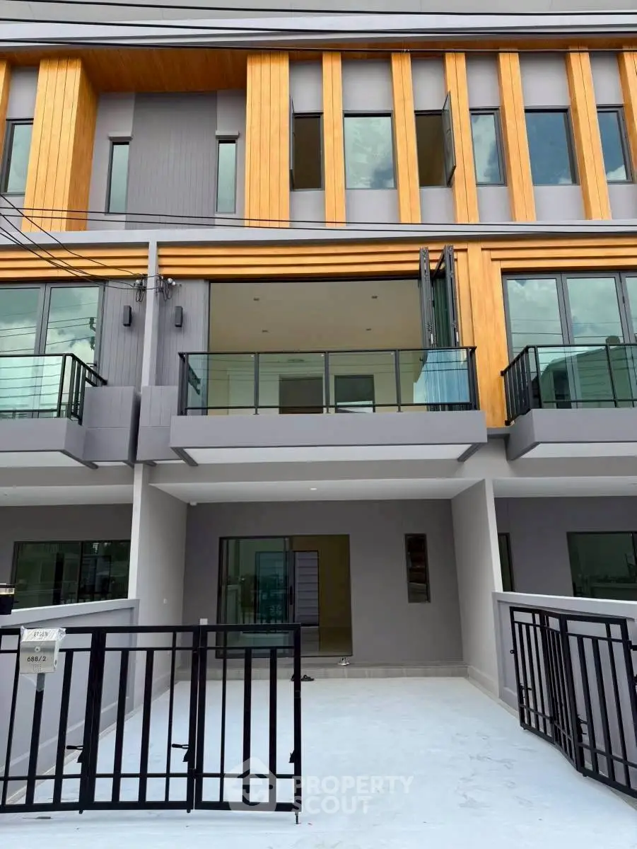 Modern townhouse exterior with glass balconies and wooden accents