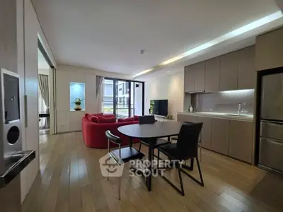 Modern open-plan living room with sleek kitchen and stylish red sofa, featuring wooden flooring and ample natural light.