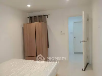 Minimalist bedroom with wooden wardrobe and open door, showcasing simple and clean design.