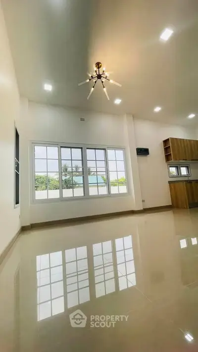 Spacious modern living room with large windows and elegant lighting, perfect for natural light lovers.