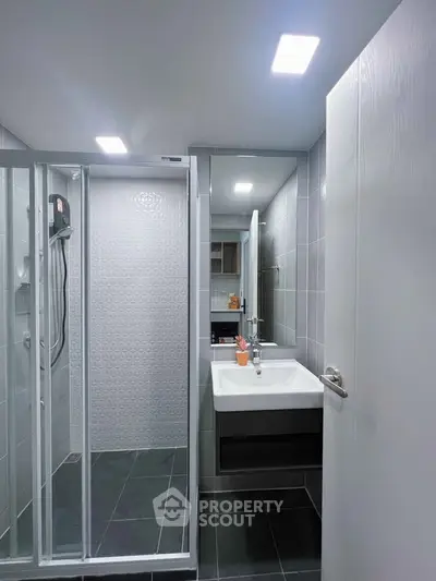 Modern bathroom with sleek shower and stylish sink in contemporary apartment.