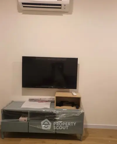 Modern living room with wall-mounted TV and air conditioning unit, showcasing minimalist design.