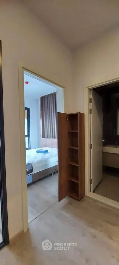 Modern apartment interior with bedroom and bathroom view, featuring sleek wooden flooring and contemporary design.